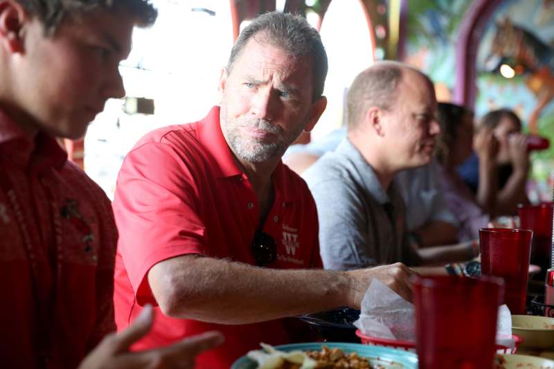 a man in a red shirt sitting at a table with other people