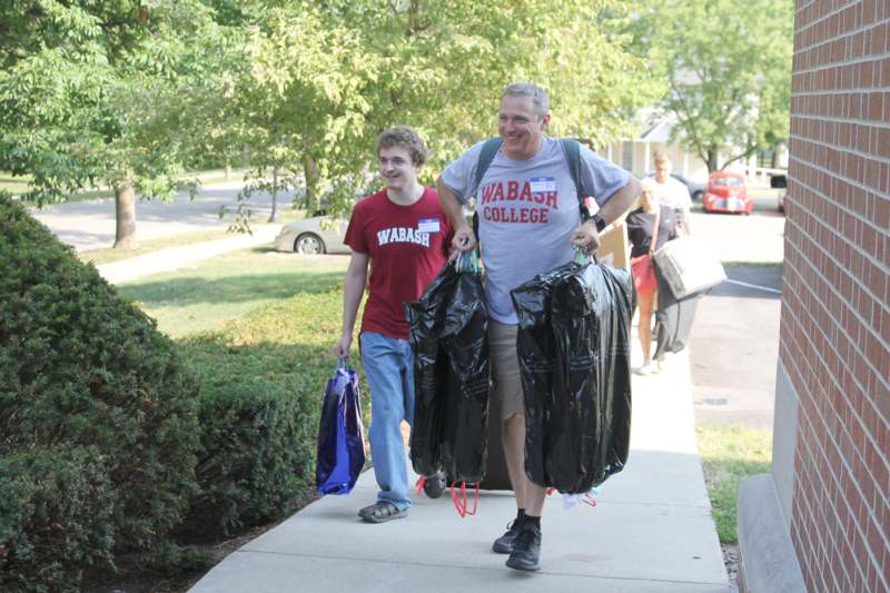 a man and boy carrying trash bags