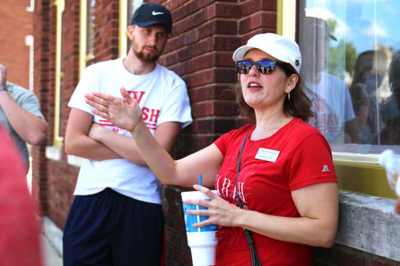a woman in a red shirt and white hat holding a cup and standing next to a man