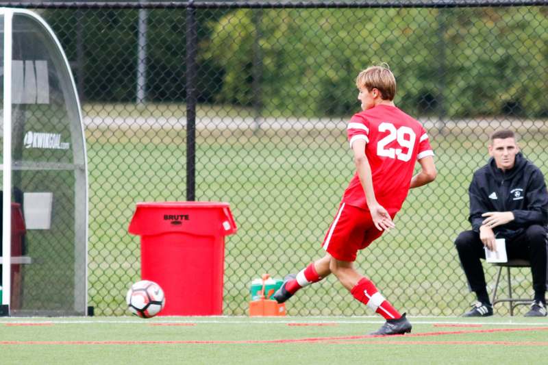 a boy in red uniform kicking a football ball