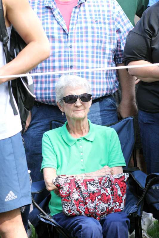 an older woman wearing sunglasses and sitting in a folding chair