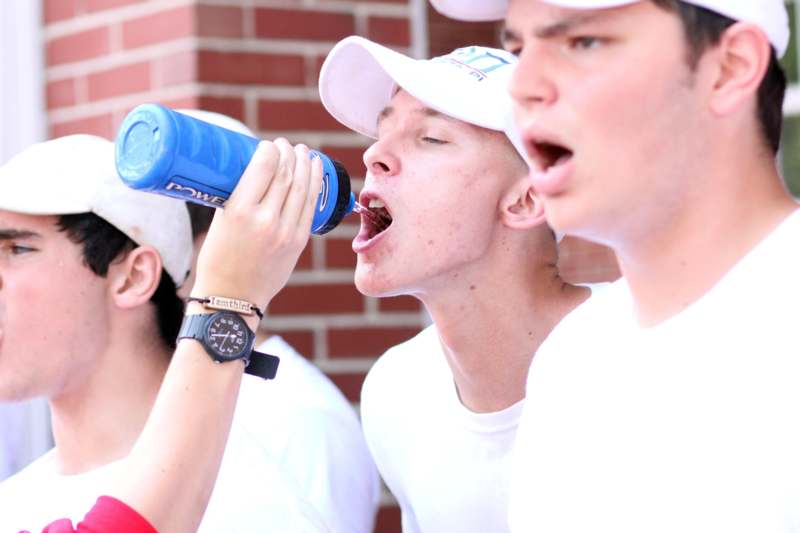a group of boys drinking from a blue bottle