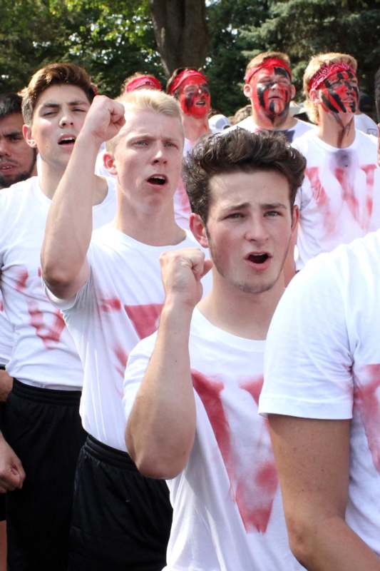 a group of people wearing white shirts with red paint on them