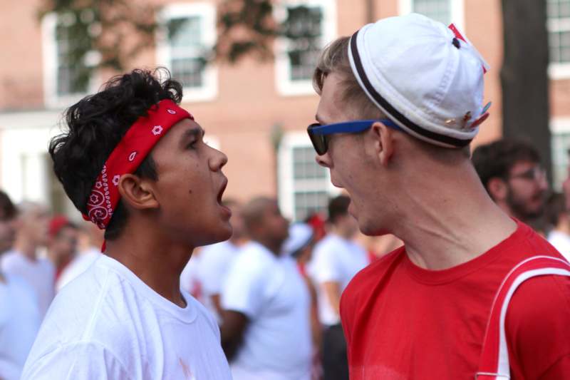 a man in a red bandana and a white hat talking to another man