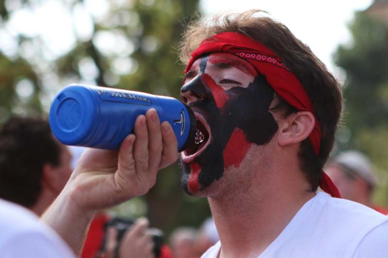 a man with face paint drinking from a blue bottle