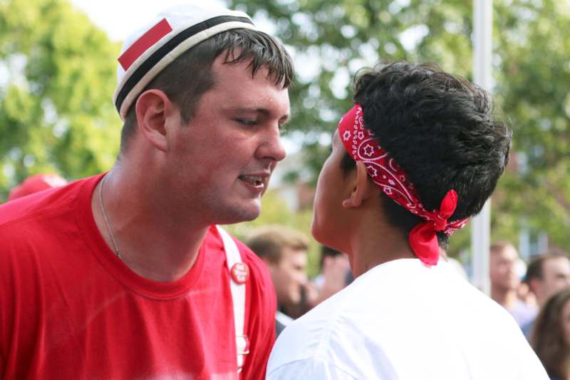 a man in a red shirt and white hat talking to a boy
