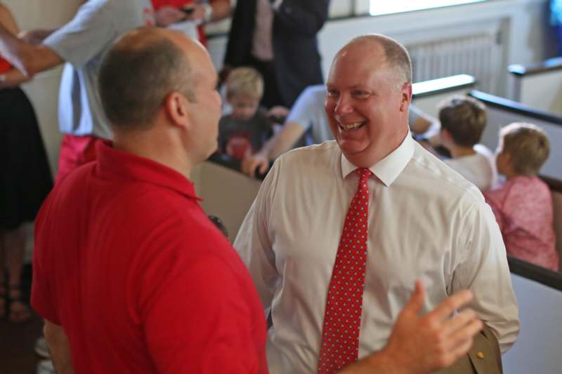 a man in a red shirt and tie talking to another man