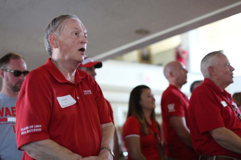 a man in red shirt speaking to a group of people