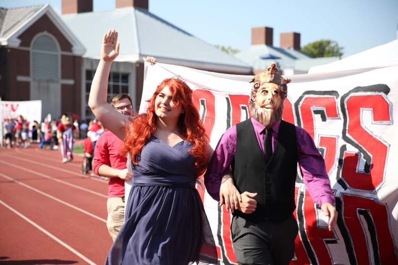 a woman in a purple dress and a man in a mask walking on a track