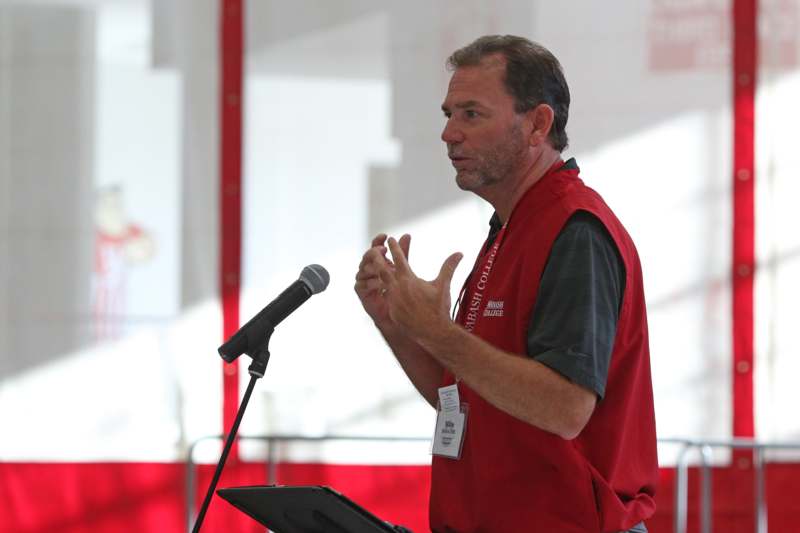 a man in a red vest talking into a microphone