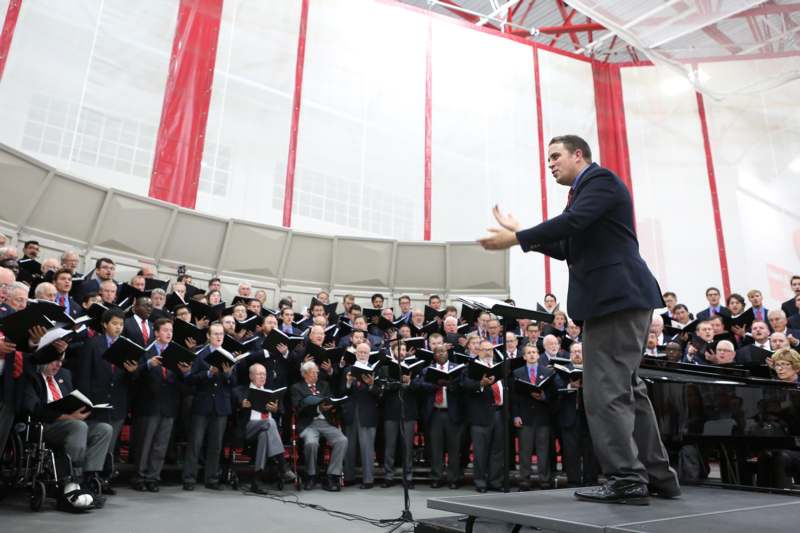 a man standing on a stage with choir in front of him