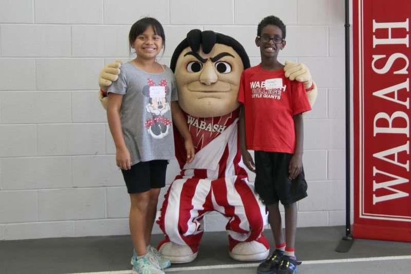 a boy and girl posing with a mascot