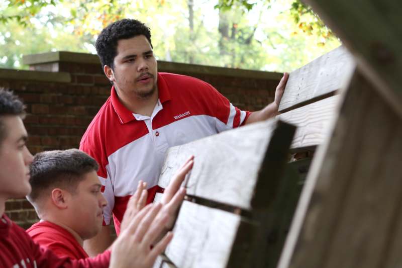 a man in red shirt touching a wooden bench