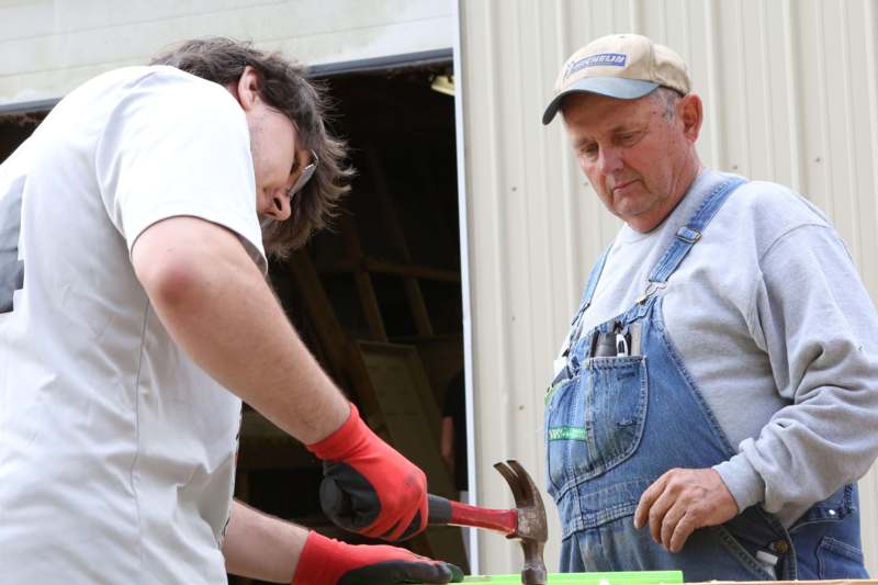 a man in overalls holding a hammer