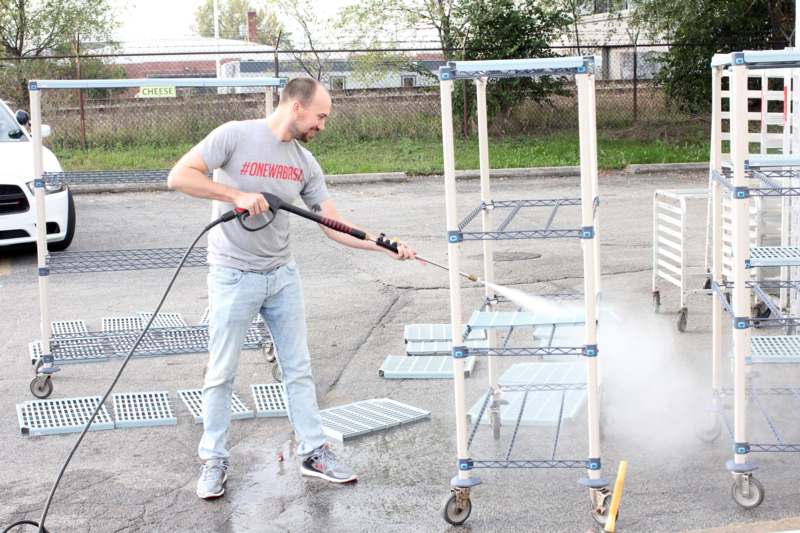 a man holding a hose and spraying water on a metal structure