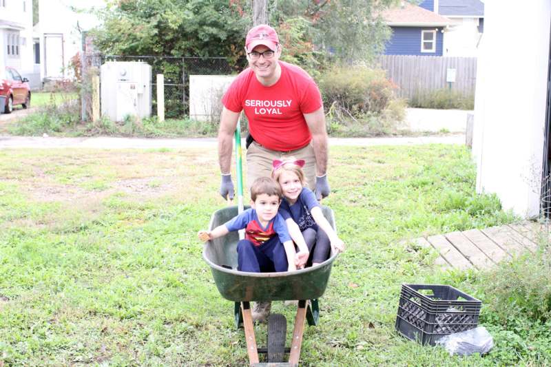a man pushing two children in a wheelbarrow