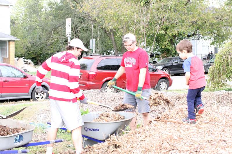 a group of people with shovels and a wheelbarrow full of leaves