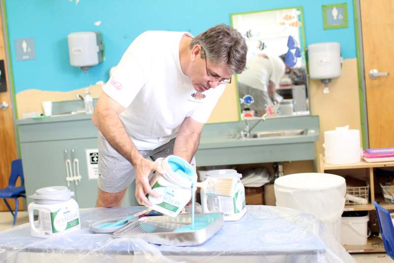 a man pouring paint into a tray