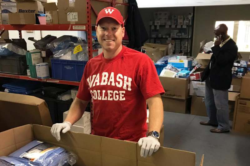 a man in a red shirt and hat holding a box