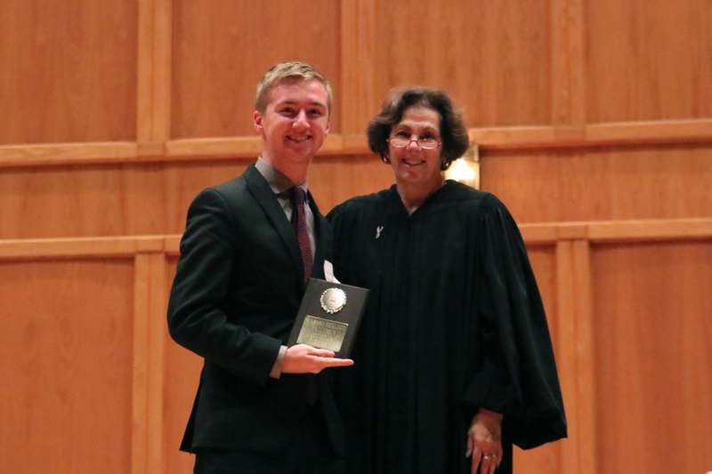 a man in a black robe holding a plaque with a woman in a black robe