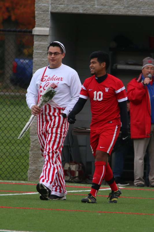 a man in red and white striped pants holding flowers and walking next to a man in red and white striped pants