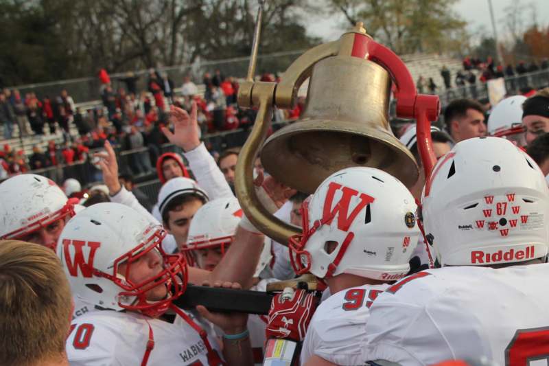 a group of football players holding a large bell