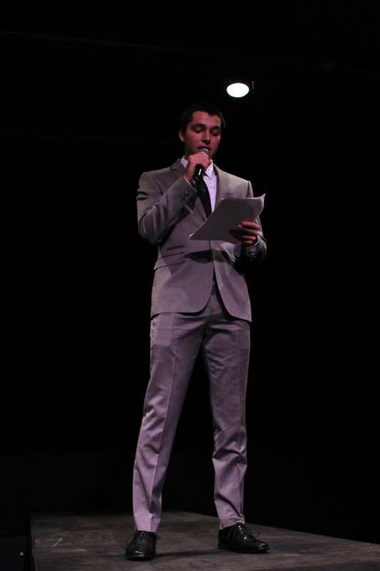 a man in a suit holding a microphone and speaking into a microphone