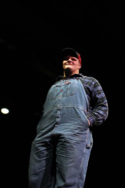 a man in overalls and a baseball cap
