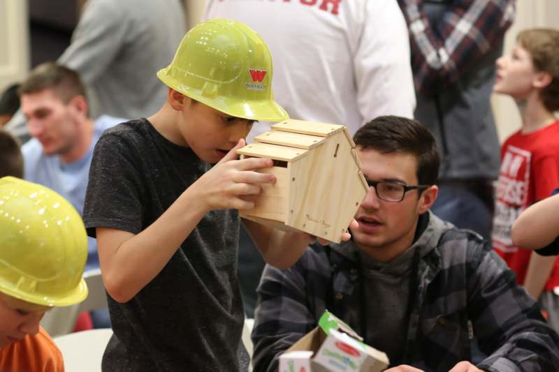 a boy looking at a wooden birdhouse
