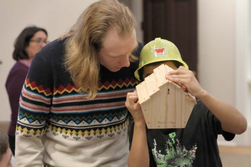 a man and boy looking at a wooden birdhouse