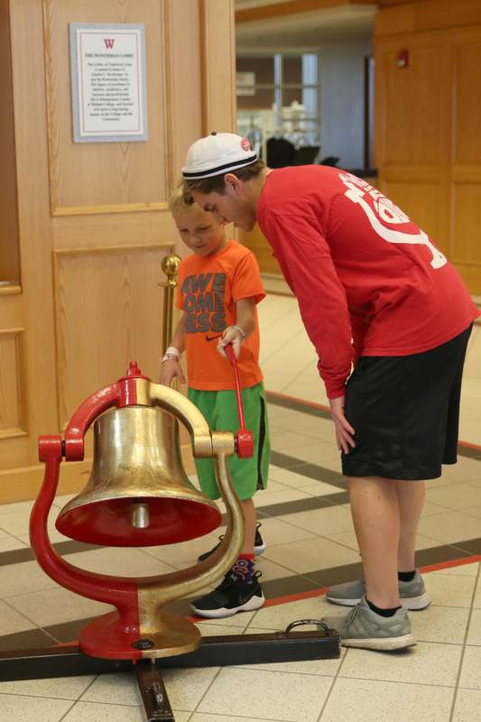 a man and boy looking at a bell