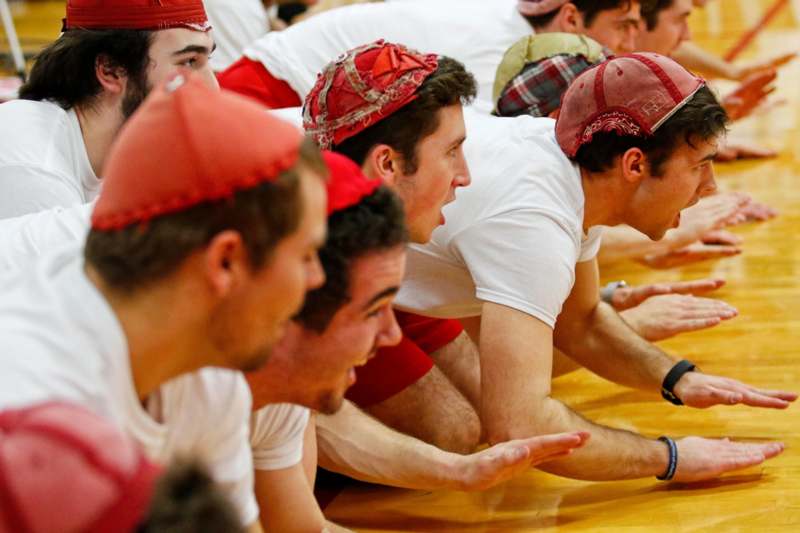 a group of men in white shirts and red hats on a floor