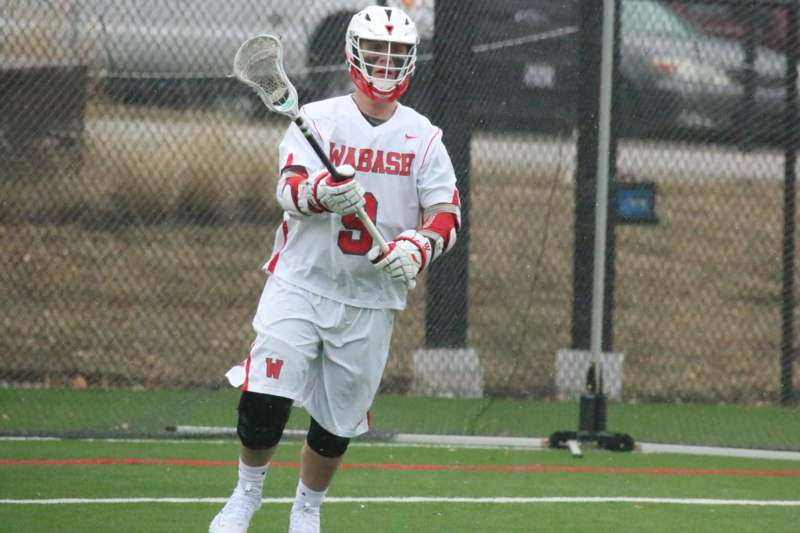 a man wearing a white and red uniform holding a lacrosse stick