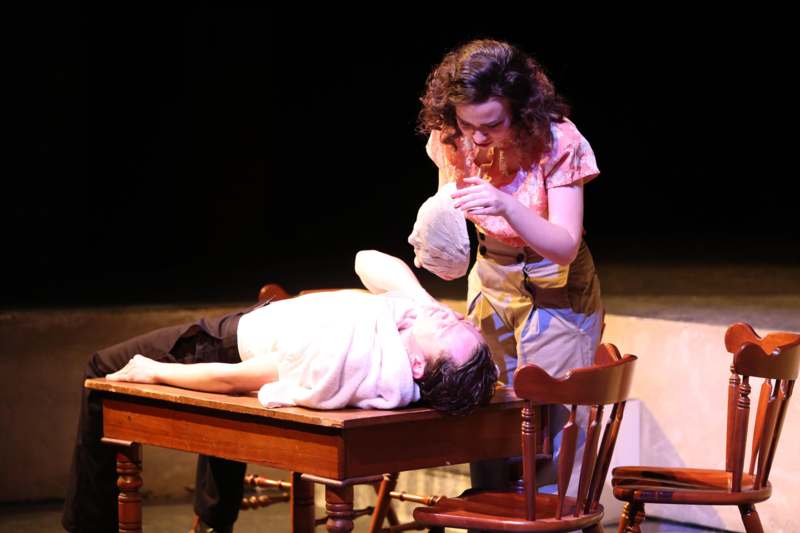 a woman standing next to a man lying on a table