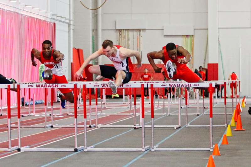 a group of men running over hurdles