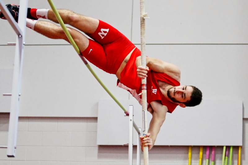a man in red shorts and a red tank top doing a high jump