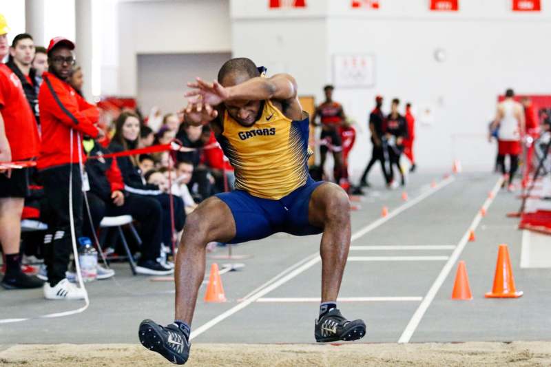 a man in a blue and yellow shirt jumping over a long jump