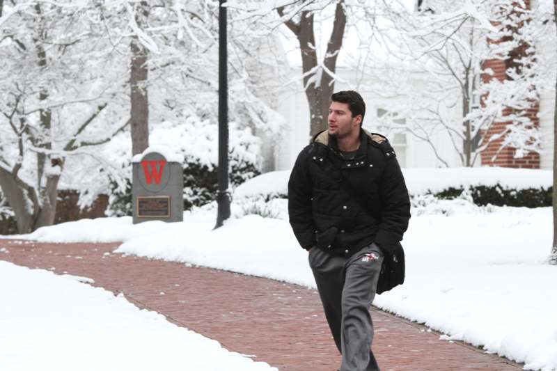 a man walking on a sidewalk in the snow
