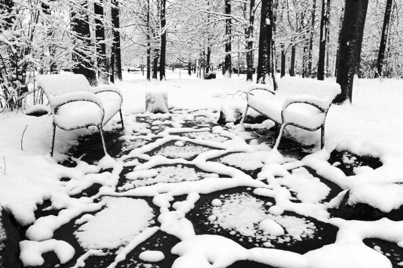 a snow covered patio with chairs and trees