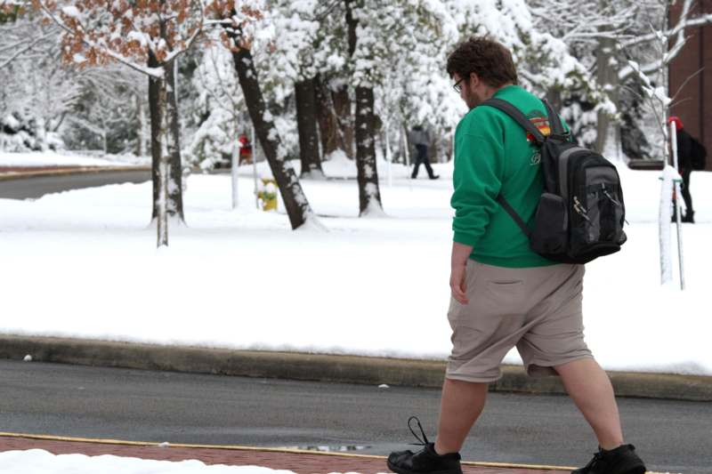 a man walking on a snowy sidewalk