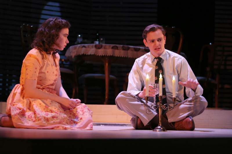 a man and woman sitting on a stage with candles