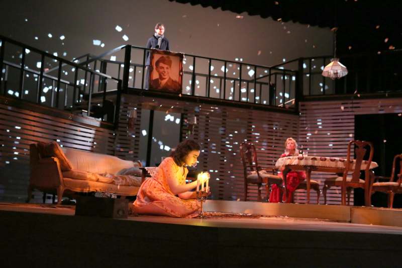 a woman sitting on a stage with a candle in front of a man