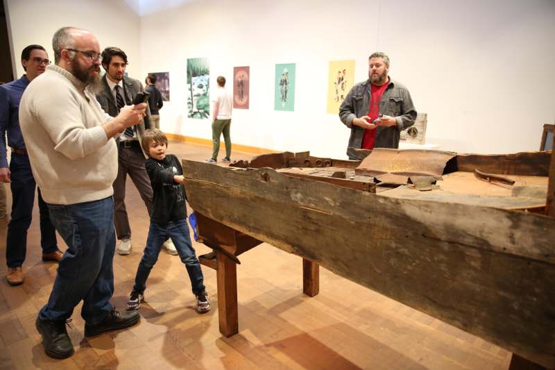 a group of people standing around a wooden object