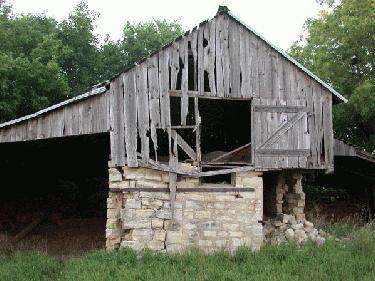 a wooden barn with a broken window with Euharlee Covered Bridge in the background