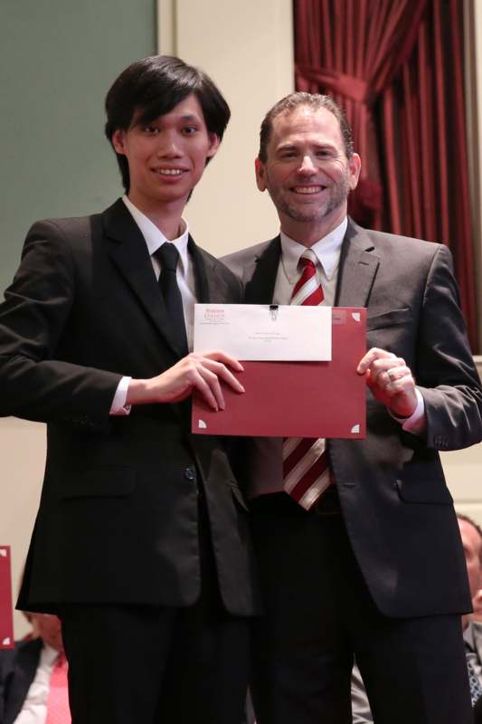two men in suits holding a red folder