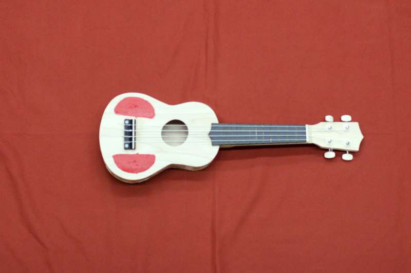a toy guitar on a red surface