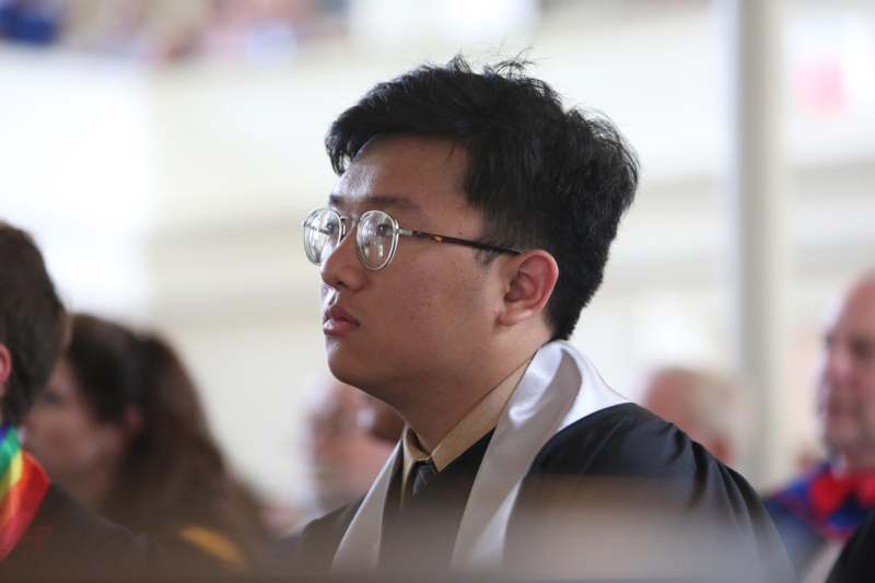 a man wearing glasses and a graduation gown