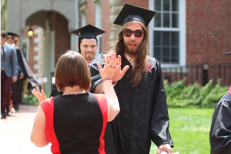 a man in a cap and gown giving a high five to a woman