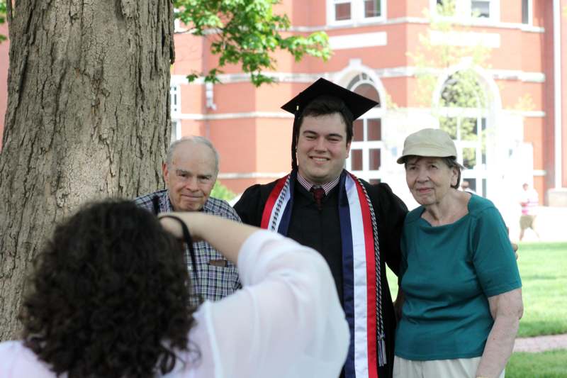 a man in a graduation cap and gown standing next to a group of people