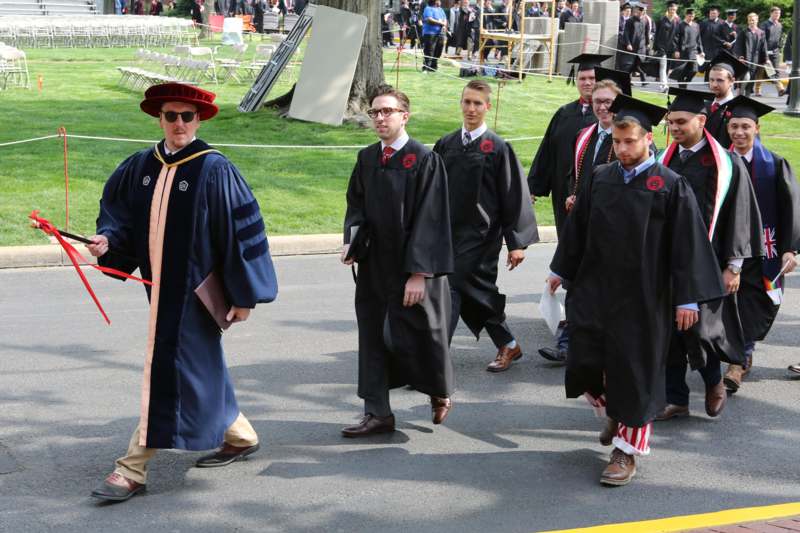 a group of people in graduation gowns walking on a street